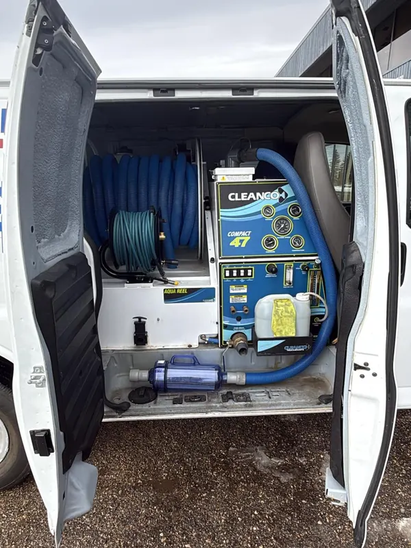 The back of the 4CJ van with both doors open, showing the cleaning machine, hose reels and water tank mounted inside